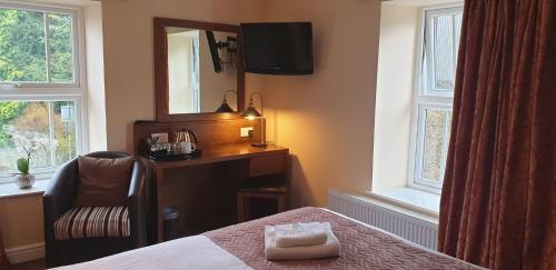 a bedroom with a bed and a chair and a mirror at Usk And Railway Inn in Sennybridge