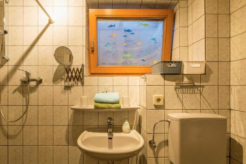 un bagno con lavandino, WC e finestra di Ferienwohnung Alina a Singen
