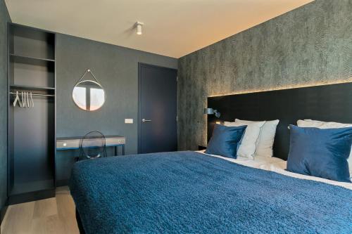 a bedroom with a large bed with blue pillows at DRL08 Luxury apartment with sauna in centre in Domburg