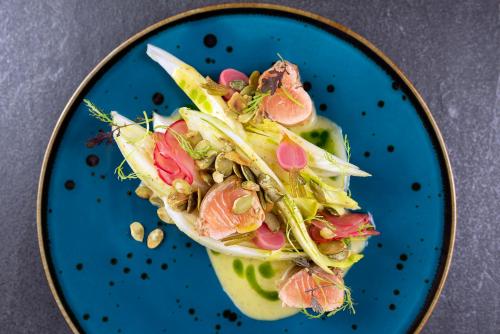 a blue plate with a salad with vegetables on it at IBB Hotel Grand Hotel Lublin in Lublin