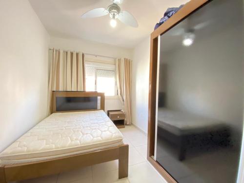 a small bedroom with a bed and a window at Lindo apartamento mobiliado in Capão da Canoa