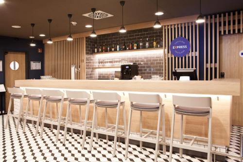 a bar in a restaurant with white stools at Holiday Inn Express Munich - Olympiapark by IHG in Munich