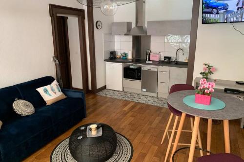 un salon avec un canapé bleu et une table dans l'établissement LE CENTRE VILLE AU CALME, à Albertville