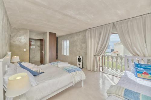 1 dormitorio con 1 cama grande y balcón en Catch of the Day, en Struisbaai