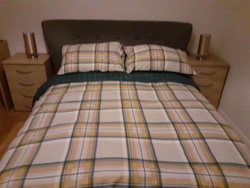 a bed with a plaid blanket and two pillows at Apartment Mary street in Porthcawl
