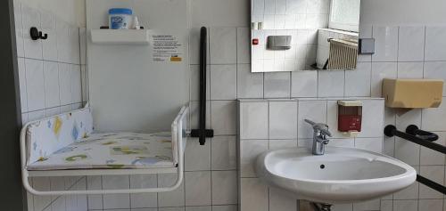 a small bathroom with a sink and a bed at Jugendherberge Fehmarn in Fehmarn