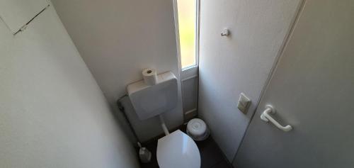 a small bathroom with a white toilet and a window at Jugendherberge Fehmarn in Fehmarn