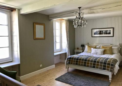 a bedroom with a bed and a chandelier and windows at Le Pigeonnier Gite in Verrières