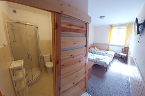 a bathroom with a walk in shower and a bedroom at Folwark Tumiany Pokoje & Restauracja in Tumiany