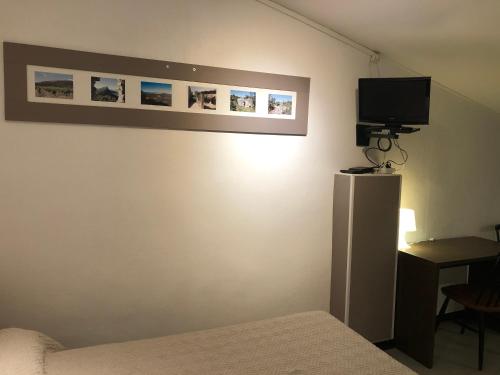 - une chambre avec un lit et une télévision murale dans l'établissement Hotel des Etuves, à Montpellier