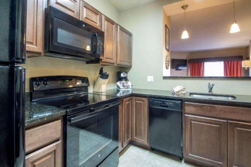 a kitchen with black appliances and wooden cabinets at Bluegreen Vacations Odyssey Dells Resort in Wisconsin Dells