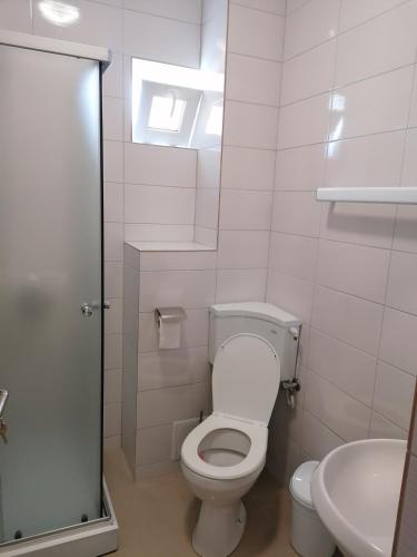 a white bathroom with a toilet and a sink at Azamara in Costinesti