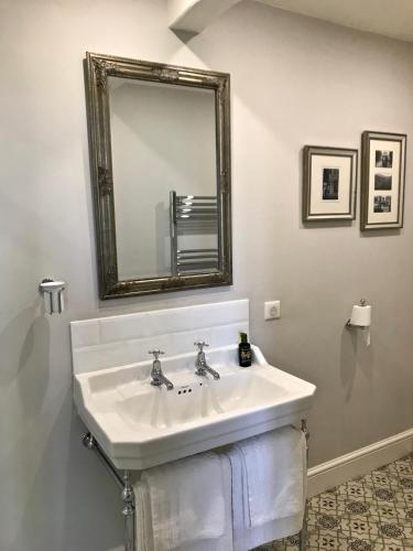 une salle de bain avec un lavabo blanc et un miroir dans l'établissement Le Pigeonnier Gite, à Verrières