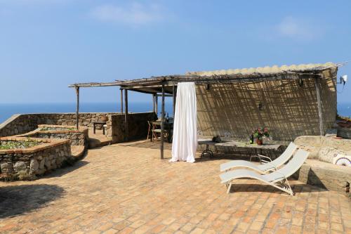 a pavilion with a table and chairs and the ocean at Case di Berto in Capo Vaticano