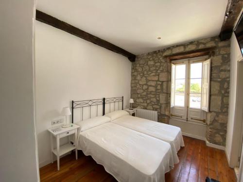 1 dormitorio con 2 camas y pared de piedra en HOSTERÍA SEÑORÍO DE BIZKAIA, en Bakio