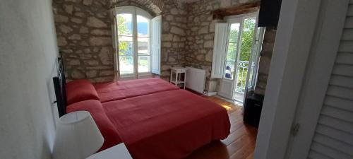 a bedroom with a red bed in a room with windows at HOSTERÍA SEÑORÍO DE BIZKAIA in Bakio