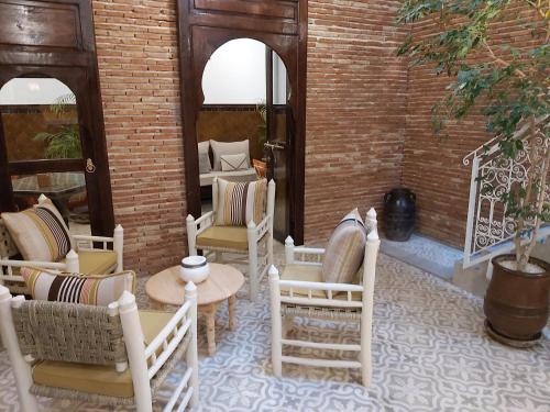 a room with chairs and tables and a brick wall at Riad Les Nuits de Marrakech in Marrakech