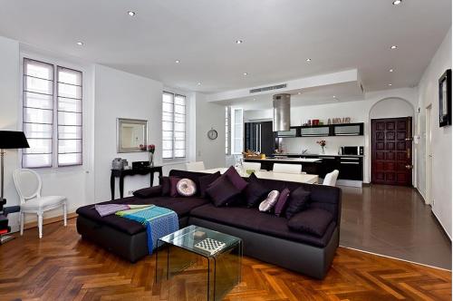 un salon avec un canapé noir et une cuisine dans l'établissement Sunlight Properties - AmourViolette - Central apartment w RARE terrace, à Nice