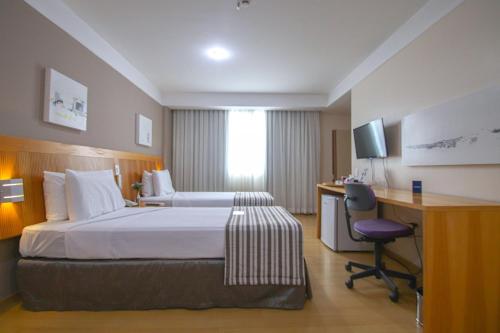 a hotel room with a bed and a desk and a computer at Belo Horizonte Plaza in Belo Horizonte
