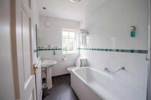 een witte badkamer met een bad en een wastafel bij Thomas Arms Hotel in Llanelli