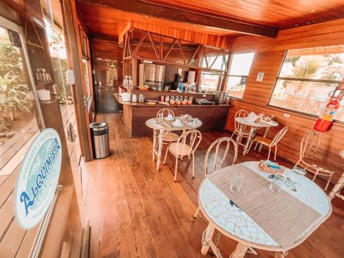 a dining room with tables and chairs and a kitchen at Pousada Alquimista in Fernando de Noronha