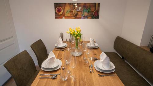 a wooden table with chairs and plates and glasses on it at DAS JOHANN Apartments im Ausseerland in Bad Aussee