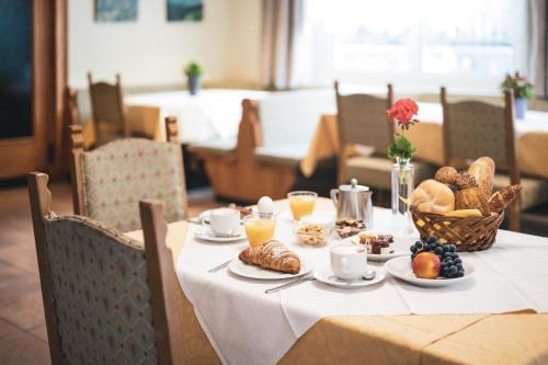 una mesa con comida para el desayuno y bebidas en ella en Hotel B&B Frohsinn en Badia