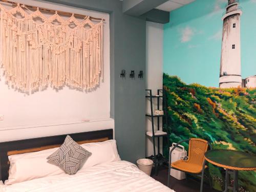 a bedroom with a bed and a painting of a lighthouse at 海島旅人 Diving Hostel in Green Island