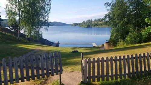 a fence with a view of a lake at Trevlig stuga nära Hovfjället in Torsby