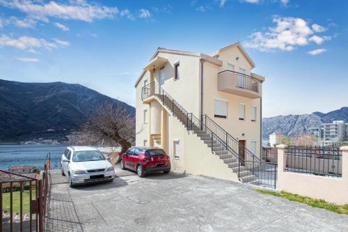 ein Gebäude mit zwei Autos auf einem Parkplatz in der Unterkunft Apartments Donkovic in Kotor