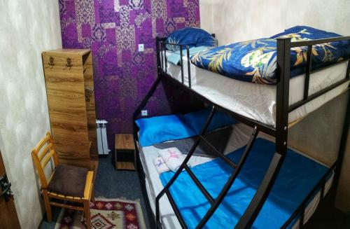 a dorm room with two bunk beds and a chair at Hostel Violet in Tbilisi City