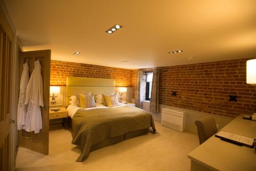 a bedroom with a bed and a brick wall at Channels Retreat in Chelmsford
