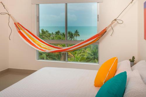 eine Hängematte, die in einem Schlafzimmer mit einem Fenster hängt in der Unterkunft Magico Apartamento Frente al Mar 3 Habitaciones AR44 in Coveñas