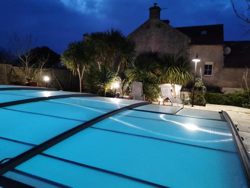 a swimming pool in front of a house at night at Normandie, mer et campagne in Ver-sur-Mer