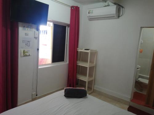 a room with a bed with a red curtain and a window at Inn Skyline Hostel in San Andrés