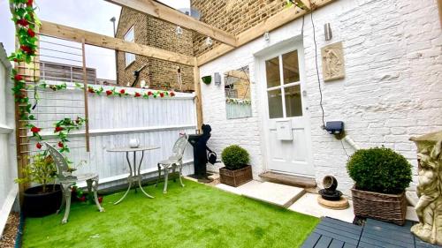 a small backyard with a lawn and a white house at Modern and cosy studio flat in London