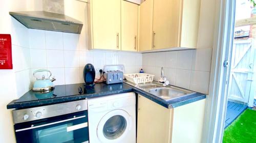 a kitchen with a washing machine and a sink at Modern and cosy studio flat in London