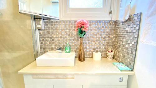 a bathroom counter with a sink and a vase of flowers at Modern and cosy studio flat in London