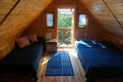a bedroom with two beds in a log cabin at Domek JEZIORACZEK in Urowo