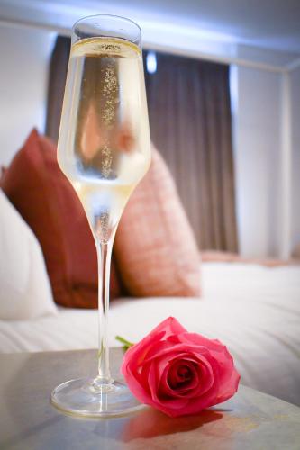 a glass of wine and a rose on a table at The Gate Cottage in Thaxted