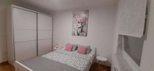 een kleine witte slaapkamer met een bed met roze kussens bij Elena apartmani in Tuzla