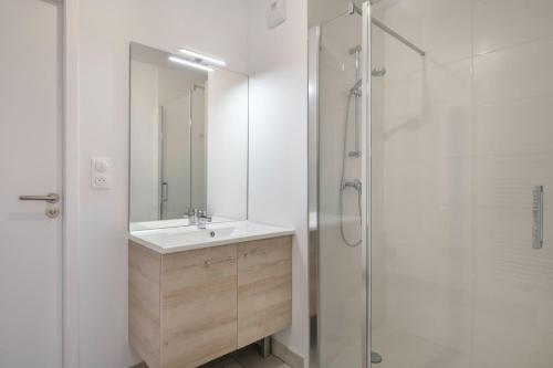 une salle de bain blanche avec un lavabo et une douche dans l'établissement Séjour pour 6 face à la grande plage de Pléneuf, à Pléneuf-Val-André