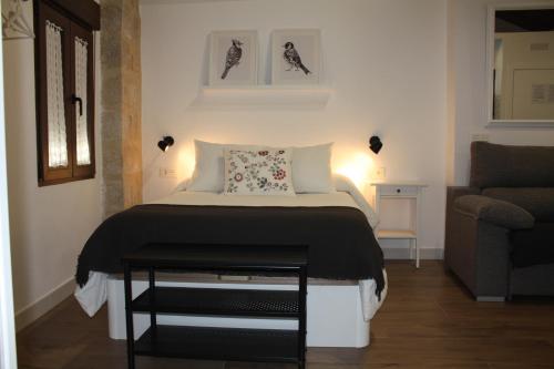 ein kleines Schlafzimmer mit einem Bett und einem Sofa in der Unterkunft Barbacana, dieciocho in Baeza