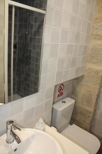 ein Badezimmer mit einem Waschbecken, einem WC und einem Spiegel in der Unterkunft Barbacana, dieciocho in Baeza