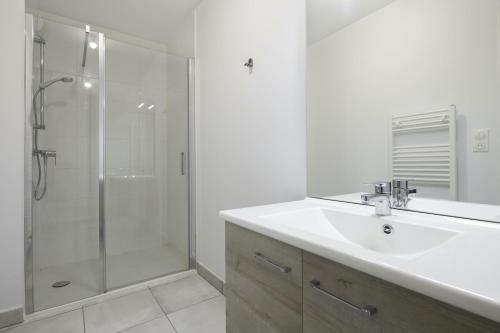 une salle de bain blanche avec un lavabo et une douche dans l'établissement Face à la mer, bel appartement pour 6, à Pléneuf-Val-André