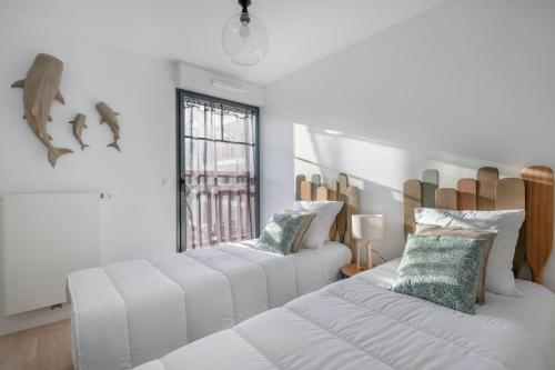 - 2 lits blancs dans une chambre avec fenêtre dans l'établissement Un sejour en appartement face a la mer a Pleneuf Val Andre, à Pléneuf-Val-André