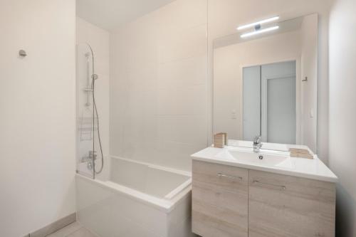 Un baño blanco con lavabo y bañera. en Bel appartement pour 4 à 50m de la plage, en Pléneuf-Val-André