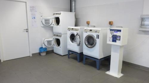 eine Waschküche mit drei Waschmaschinen sowie einer Waschmaschine und einem Trockner in der Unterkunft Appart-Hotel Mer & Golf City Ile de Nantes in Nantes