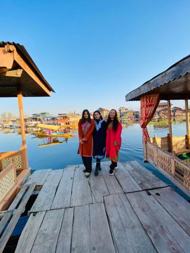 three women standing on a dock near the water at Houseboat New Suzan in Srinagar