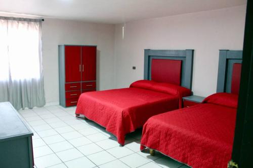 1 dormitorio con 2 camas con colchas rojas y ventana en Departamento completo en Creel, en Creel
